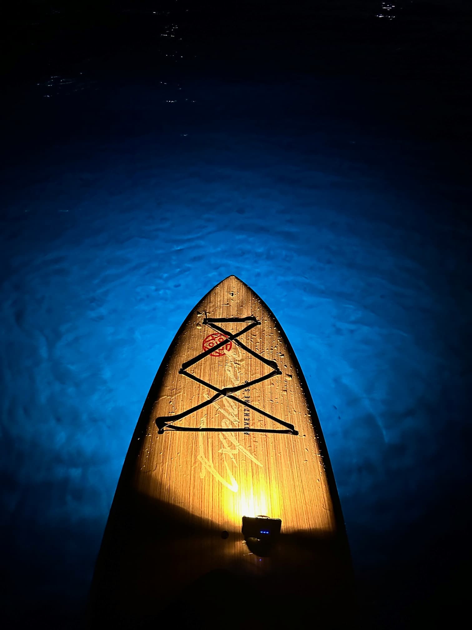 E-Sea Light waterproof paddle board light suction mounted onto a Yolo paddle board shining into the ocean floor at night